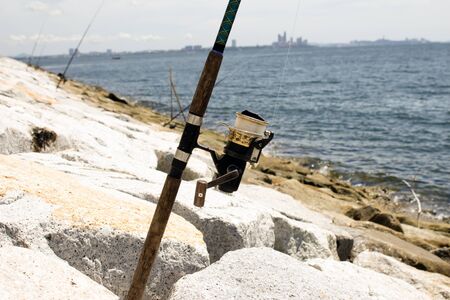 Fixed fishing rod set up on a beach near the surf on the incoming tide