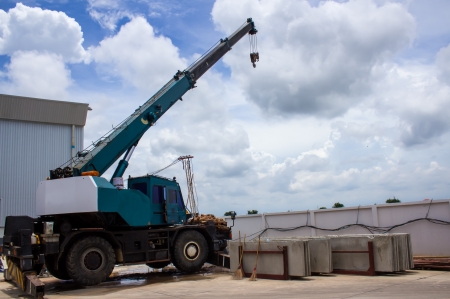 automobile crane with risen telescopic boom outdoors over blue sky