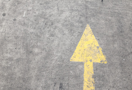 yellow way arrow pointing in directions symbol on a ground road surfaceの写真素材