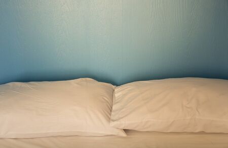 An unmade bed with white linens background blue woodの写真素材