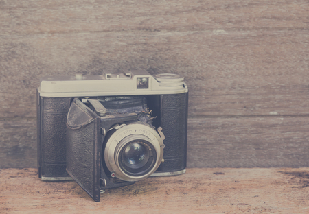 Old retro camera on vintage wooden boards abstract background. Vintage filter.の写真素材