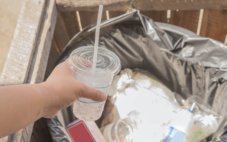 Woman's Hand throwing scarp of cup into recycling bin, hand holding piece of garbage in trash canの写真素材