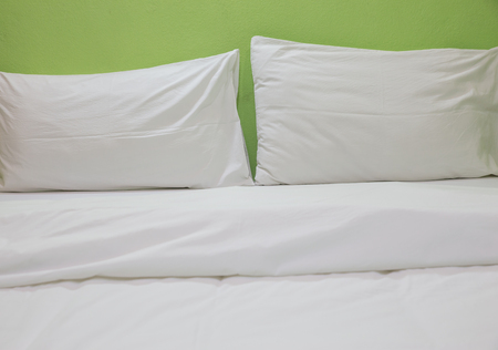An unmade bed with white linens background greenの写真素材