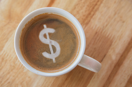 Dollar in cup of coffee with in a white cup on wooden background.の写真素材