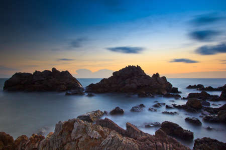 Landscape sunset sea waves line impact rock on the beach の写真素材