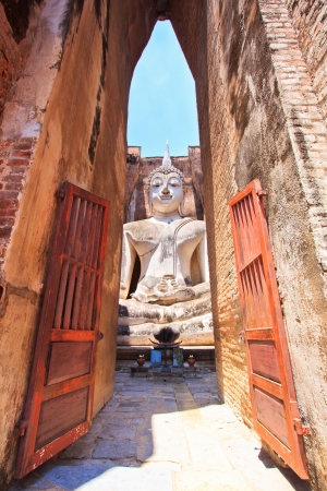 Giant statue of a seated Buddha with tapered fingers covered with gold leaves in Sukhothai Historical Park - Thailand の写真素材