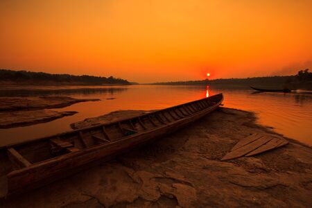 Silhouettes landscape view sunset and old wooden boats in mekong river ubon ratchathani province thailand の写真素材