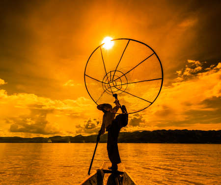 Myanmar Inle lake fisherman on boat catching fish by traditional net in village Inlay Shan state of Myanmarの写真素材
