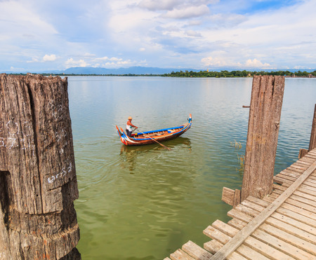 AMARAPURA, MYANMAR - Aug 26th, 2014: An unidentified man rows his boat on Aug 26th, 2014: in Amarapura, Myanmar. Amarapura is famed for the longest teak bridge in the world.のeditorial素材