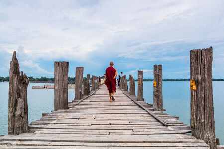 U Bein Bridge, Myanmar-Aug 26th, 2014: Myanmar monks walk on U Bein Bridge where is the oldest and...