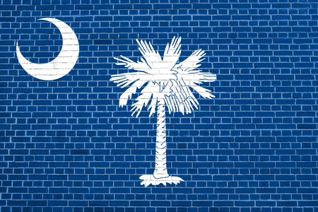 South Carolinian official flag, symbol. American patriotic element. USA banner. United States of America background. Flag of the US state of South Carolina on brick wall texture backgroundの写真素材