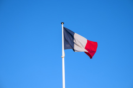 French national official flag on blue sky background. Symbol of France. Patriotic french banner, design. Flag of France on flagpole waving in the windの写真素材