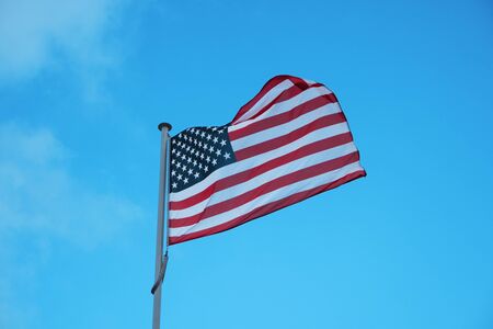 American national official flag on blue sky background. Symbol of the United States. Patriotic US...