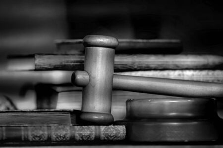Court wooden hammer and old books on a wooden table - black and whiteの写真素材
