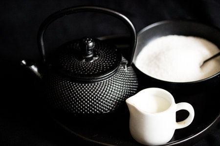 Teapot and cup of sugar on black background, stock photoの写真素材