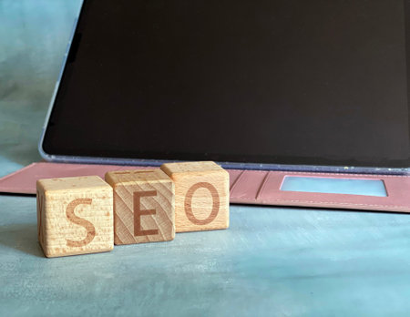 The word SEO is written on wooden cubes with a laptop in the background. Search engine optimization conceptの写真素材