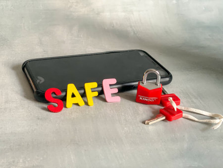 SAFE word on smart phone with red lock and key chain.の写真素材