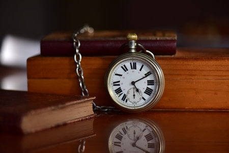 Vintage pocket watch and books on a dark background. Time conceptの写真素材