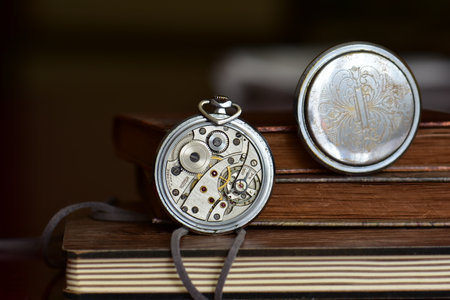 Close up of an old pocket watch and old books on the table