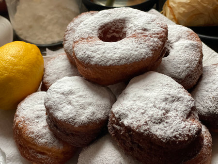 delicious donuts sprinkled with powdered sugar and a lemon on a table