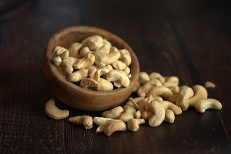 Roasted cashew nuts in wooden bowl on dark wooden background.の写真素材