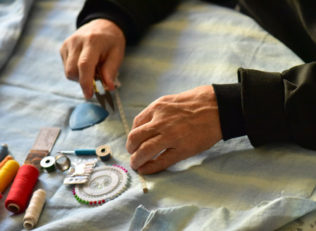 Close-up of a man's hands sewing on a fabric.の写真素材
