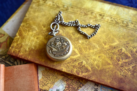 Old book and a pocket watch with a crown on a chain.