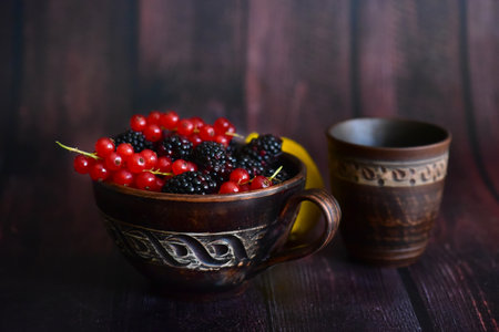 Cup of blackberry and red currant on dark wooden background.の写真素材