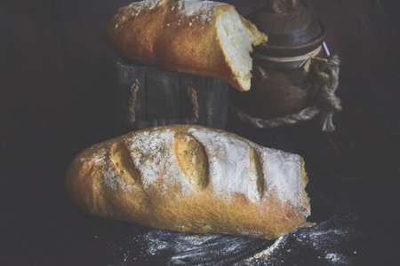 Freshly baked bread on a dark wooden background. Vintage style.