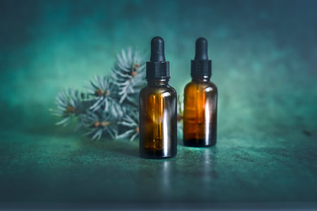 Spruce essential oil in a glass bottle on a green background.の写真素材