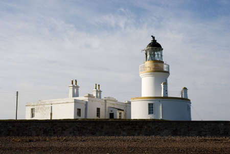 a horizontal image of a lighthouse and dwellings on the east coast of scotlandの写真素材