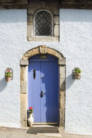 a vertical image of a blue door against a white building with flowerpotsの写真素材