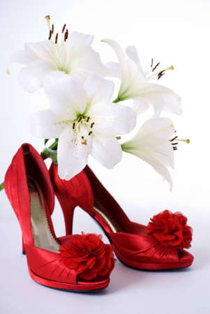 a vertical image of red satin high heel shoes and four white lilliesの写真素材