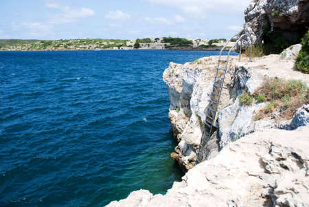 a horizontal image of a set of aluminium ladders leading down the cliff face to the seaの写真素材