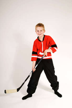a vertical image of a young boy with his hockey top and standing with his hockey stick against a plain backgroundの写真素材