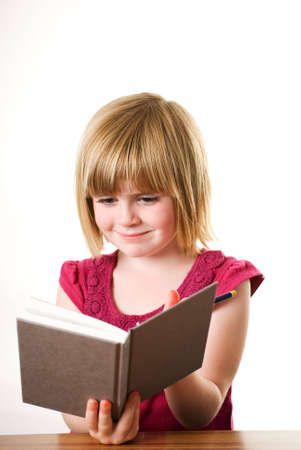 a vertical image of a pretty little blonde girl reading a book isolated on a white backgroundの写真素材