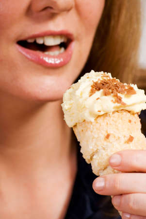 a vertical image of a woman eating a tasty  cake focus on the pastryの写真素材