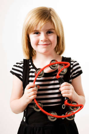a vertical image of a young girl holding a cresent shaped tambourineの写真素材