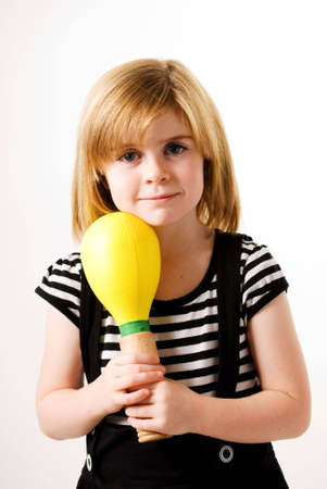 a vertical image of a pretty little girl holding a yellow musical shaker
