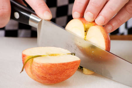 a horizontal image of a knife cutting an apple in halfの写真素材