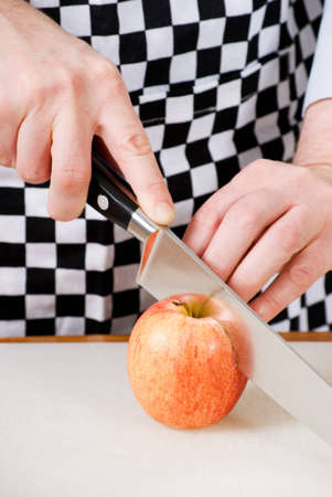 a vertical image of a cook cutting an apple in halfの写真素材