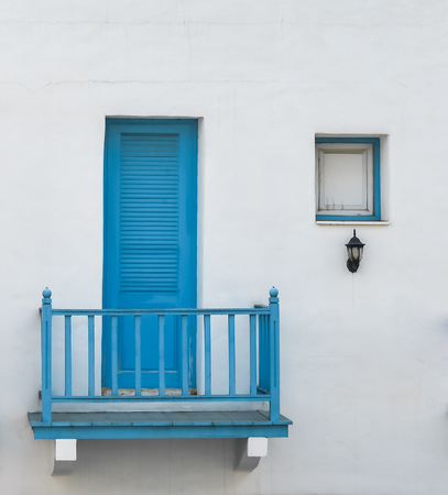 closed blue door and window on two floor on white wallの写真素材