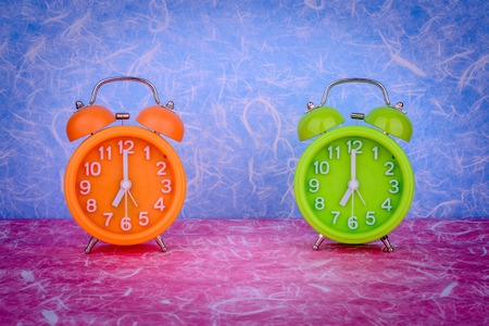 retro orange and green alarm clock on table with colorful wall backgroundの写真素材