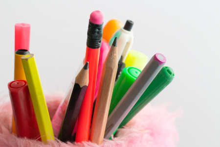 colored pencils in pink pencil holder on white backgroundの写真素材
