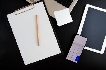 lap top, tablet, calculator and note papers on black backgroundの写真素材