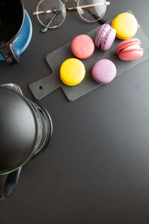 french press, coffee in cup, macarons, accessories on black backgroundの写真素材