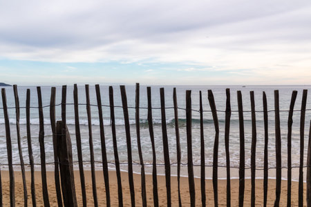Mediterranean coastline, winter. Beach in winter seen through wooden sand fences on the dunes, with...