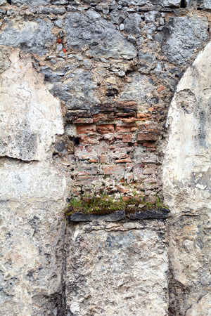 Interesting arch shape made of brick, stone and rocks, even some flowers grow on the base of itの写真素材