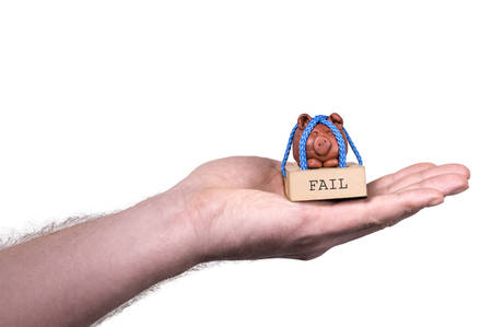 Hand holding tied piggy on a wooden base.の写真素材