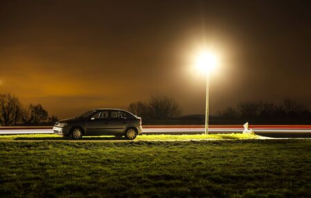 Parked car at night with light trailsの写真素材